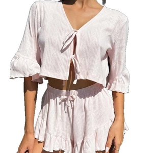 Women's pink two-piece knit lounge set featuring ruffled hem and tie-front top
