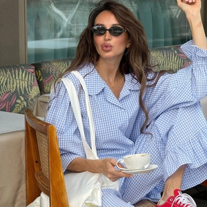 Blue and white gingham loungewear set with ruffled cuffs worn by a model in a cafe