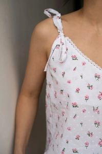 Détail d'un caraco blanc avec imprimés fleurs roses et dentelle délicate au col en V