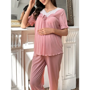 Close-up of pink maternity pajamas set with white lace V-neck and delicate bow detail