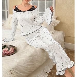 Detail of white polka dot pajama set featuring black lace trim and off-shoulder design