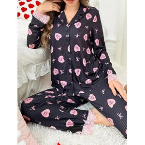 Close-up of heart print pajamas with pink lace trim and Nice Day text on soft black fabric