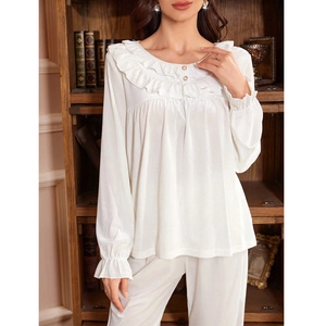 Pyjama en satin blanc élégant avec col et poignets à volants dans une chambre douillette