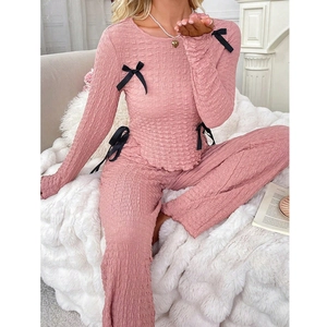 Pink popcorn fabric pajama set for women with black decorative bows and ruffled cuffs