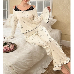 Chic women polka dot pajama set with lace trim and bow accent in a cozy bedroom setting