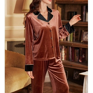 Detail of caramel velvet pajamas featuring black contrast lapels and gold piping accents