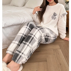 Detail von weichem Fleece-Pyjama-Oberteil mit Bärenstickerei und karierter Flanellhose