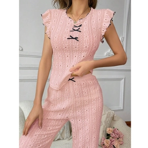 Detail of pink eyelet lace pajamas with delicate black bows and ruffled sleeve texture
