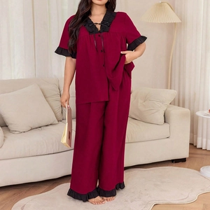 Detail of burgundy pajama set featuring V-neckline with black ruffled edges and bow tie