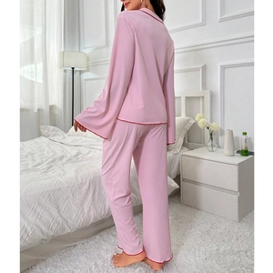 Pink ribbed pajama set with red wavy trim, long sleeves and pants in modern bedroom setting