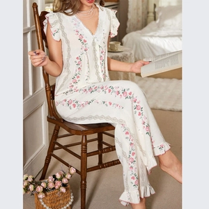 Elegant floral pajama set with V-neck lace trim and ruffled cuffs in a cozy home setting
