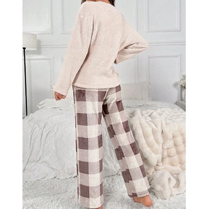 Pyjama polaire femme avec haut rose et pantalon à carreaux dans une chambre cosy