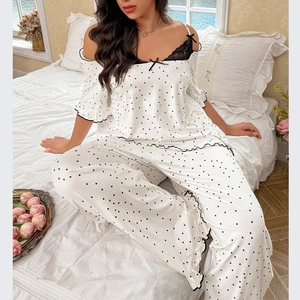 Women's white polka dot pajama set with lace trim and bow details in bedroom setting