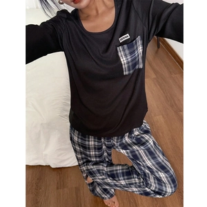 Détail du haut de pyjama à col rond avec poche à carreaux et étiquette design blanche