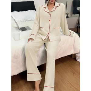Détail d'un pyjama beige à manches longues avec passepoil rouge et poches avant