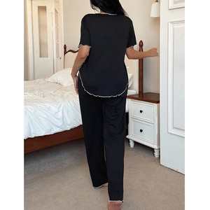 Women's black short sleeve pajama set with white wave edges and lounge pants in bedroom