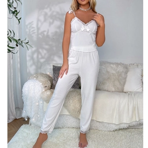 Macro detail of white ribbed camisole pajama set with delicate lace trim and bow accent