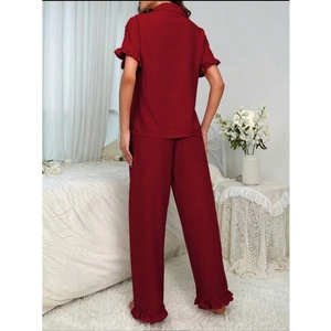 Detailansicht eines weinroten Pyjama-Sets mit Rüschenkanten an Ärmeln und langer Hose