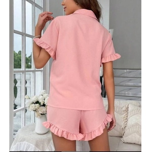 Detail shot of pink summer pajamas featuring delicate ruffle trim on sleeves and shorts