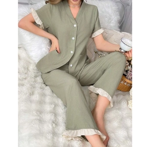 Close-up of green cotton pajamas with V-neck, white buttons and contrast ruffle hem
