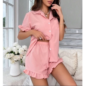 Detail of pink pajama set with ruffled edges and button-down short sleeve lapel shirt