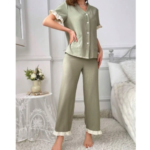 Detail view of V-neck sage green pajamas with white ruffle trim and twin pocket design