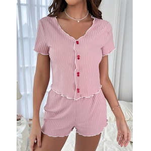 Détail d'un pyjama en maille côtelée rose avec volants blancs et boutons rouges