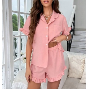 Detail of pink cotton pajamas set with ruffled trim and button-down short sleeves