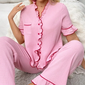 Detail of pink crepe pajamas with red contrast piping and ruffle trim on the V-neck cardigan