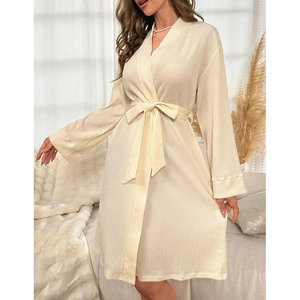 Détail d'un peignoir crème à col en V avec ceinture et tissu texturé élégant