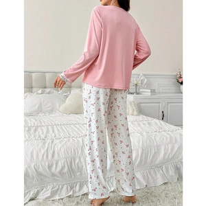 Schicker rosa Schlafanzug für Damen mit Spitzenärmeln und floraler Hose im Schlafzimmer