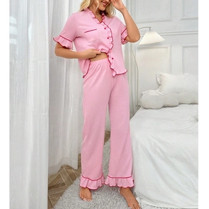 Detail of pink pajama set with red ruffle trim shown in a cozy bedroom setting