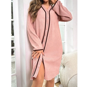 Pink pleated long-sleeve pajama dress with V-neck and contrast brown trim in a home setting