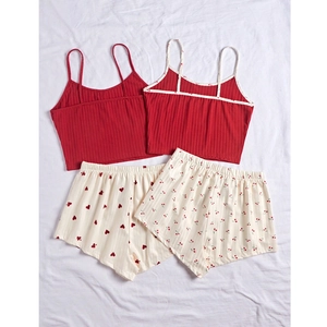 Flat lay of red summer pajama sets featuring heart and cherry prints on white fabric