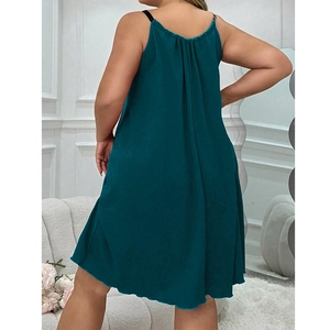 Detail of dark teal pleated slip dress with thin black straps and back ruffle design
