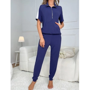 Detail eines marineblauen Strick-Pyjama-Sets mit Kontraststreifen und halbem Reißverschluss