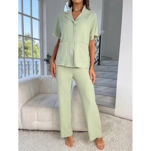 Detailed texture of green seersucker pajama set with white piping and front pockets