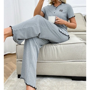 Détail du pyjama gris avec bordure ondulée, écusson lettre et texture en maille côtelée