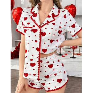 Women's heart print pajama set with short sleeves and red wavy trim in a cozy setting