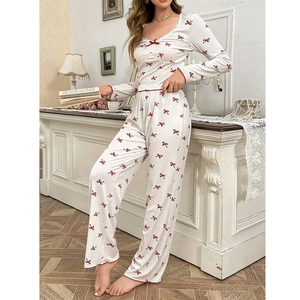 Détail du pyjama col en V avec imprimé nœuds rouges et bordure en dentelle fine