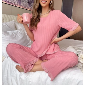 Pink two-piece pajama set with pleated fabric and delicate lace trim in a cozy bedroom