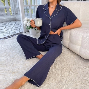 Detailed view of dark blue textured pajamas with white piping and button closure