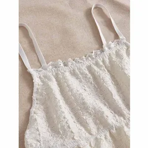 Close-up of white textured camisole featuring delicate lace trim and thin shoulder straps