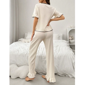 Detail of ruffled cuffs and black contrast piping on cream short sleeve pajama top