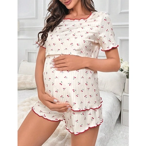 Women's cherry print maternity pajama set with ruffled trim in a cozy bedroom setting