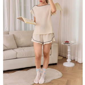 Detail of beige two-piece loungewear featuring elegant black piping and crew neck design