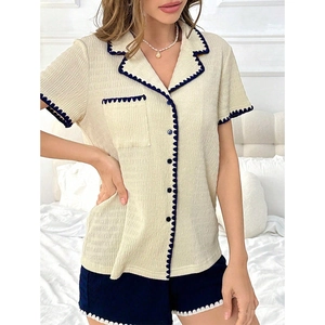 Detail of beige pajama set featuring contrast navy wavy trim and textured fabric