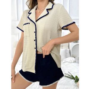 Women's pajama set featuring beige lapel short sleeve top and navy shorts in bedroom