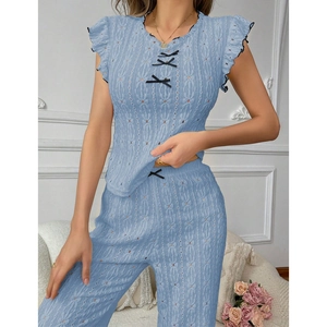 Detail of light blue knit pajamas featuring crochet texture and black ribbon bows