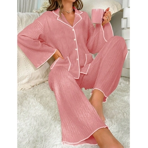 Close-up of pink pleated pajama set with white piping and button detail for women